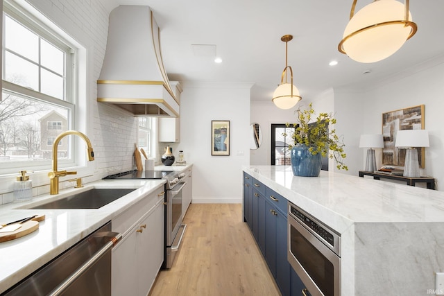 kitchen featuring blue cabinets, a sink, tasteful backsplash, appliances with stainless steel finishes, and custom exhaust hood