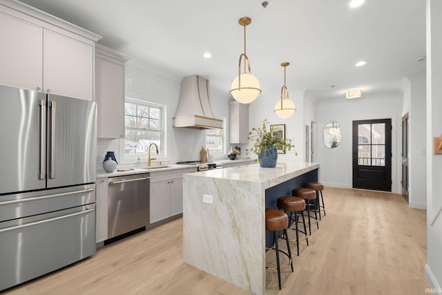 kitchen with premium range hood, a sink, tasteful backsplash, a center island, and appliances with stainless steel finishes