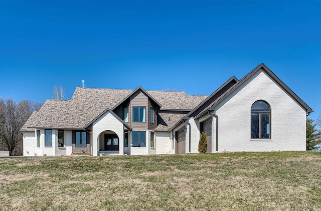 view of front of house featuring brick siding, a front yard, and a garage