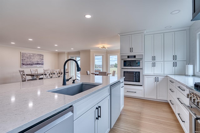 kitchen featuring dishwasher, ornamental molding, light stone counters, white cabinetry, and a sink