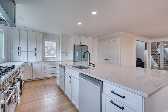 kitchen featuring white cabinetry, fridge, light wood-type flooring, and a sink