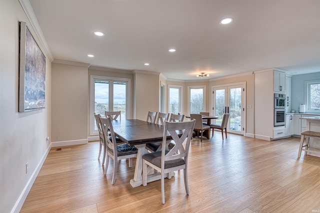 dining area featuring french doors, a healthy amount of sunlight, ornamental molding, and light wood finished floors