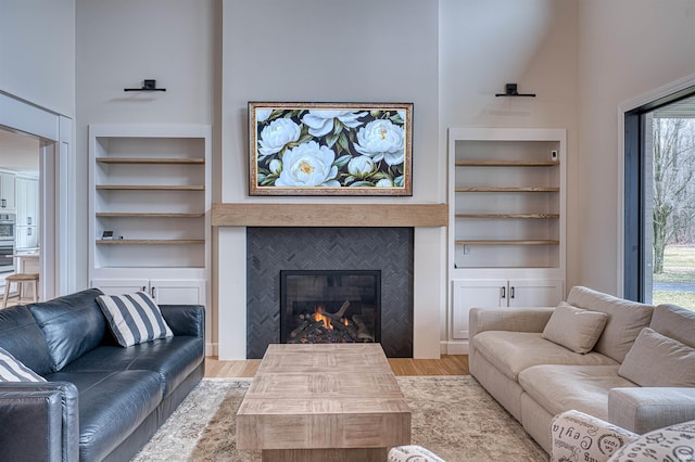 living area with built in features, a high ceiling, wood finished floors, and a fireplace