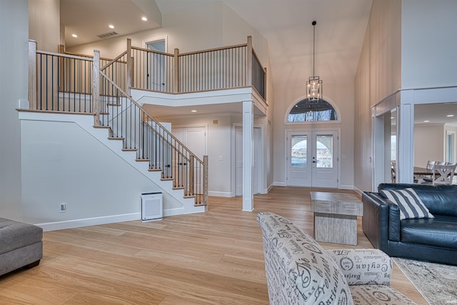 foyer featuring stairway, light wood-style floors, and a towering ceiling