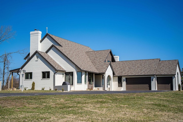 view of front facade with brick siding, a chimney, and a front lawn