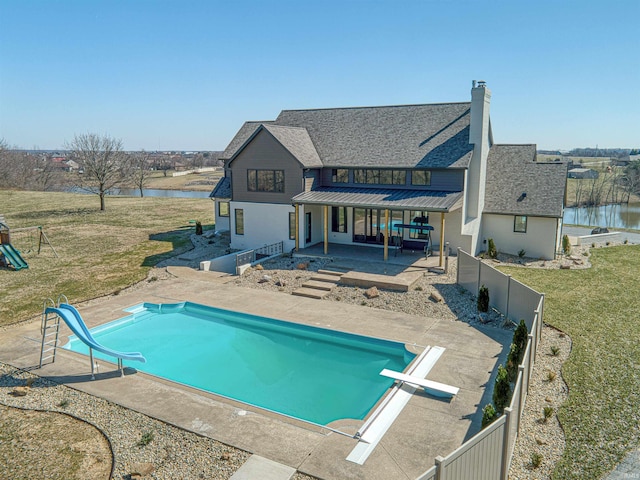 back of property featuring metal roof, a water view, a yard, and a standing seam roof