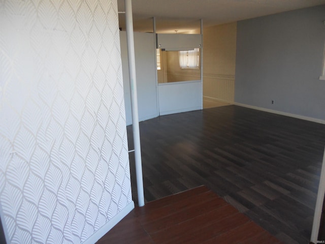 empty room with wood finished floors and a wainscoted wall