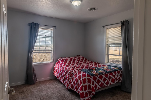 carpeted bedroom featuring baseboards, visible vents, and a textured ceiling