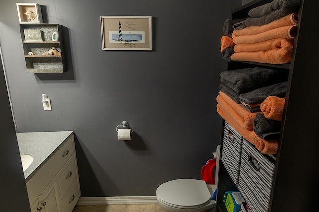 bathroom with toilet, vanity, and baseboards