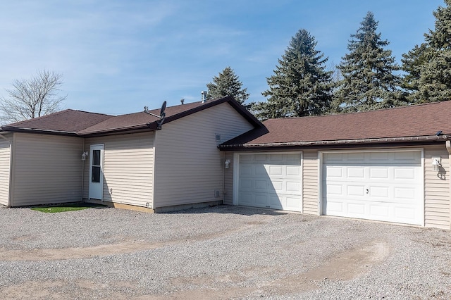 exterior space featuring a garage, driveway, and a shingled roof