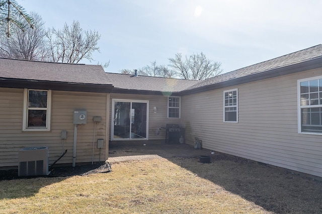 back of property featuring a yard, roof with shingles, and central AC