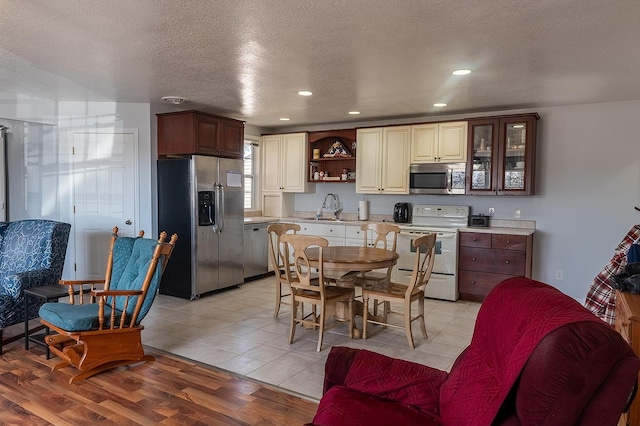 kitchen featuring a sink, open shelves, stainless steel appliances, light wood finished floors, and light countertops