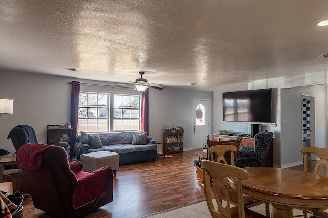 living room featuring wood finished floors, baseboards, visible vents, ceiling fan, and a textured ceiling