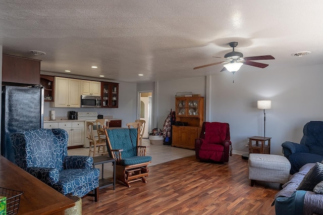 living area with light wood-style flooring, recessed lighting, visible vents, and a textured ceiling