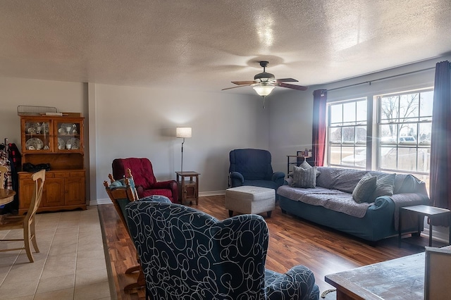 living room featuring light wood-type flooring, baseboards, a textured ceiling, and a ceiling fan