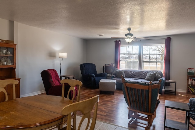 living area featuring baseboards, wood finished floors, a textured ceiling, and ceiling fan