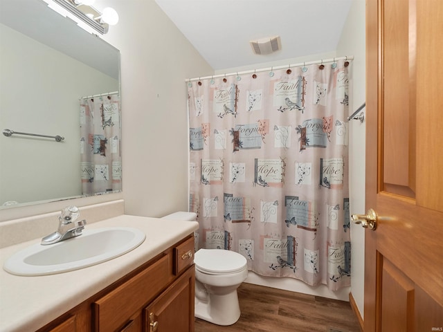 bathroom with vanity, toilet, wood finished floors, and visible vents