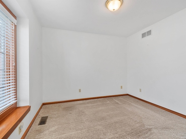 unfurnished room with carpet, visible vents, and baseboards