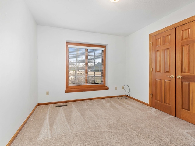 unfurnished bedroom featuring visible vents, baseboards, a closet, and carpet flooring