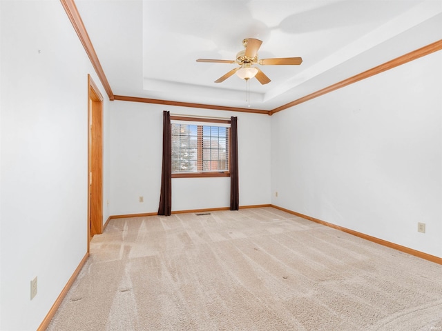 unfurnished room with a tray ceiling, light carpet, baseboards, and ornamental molding