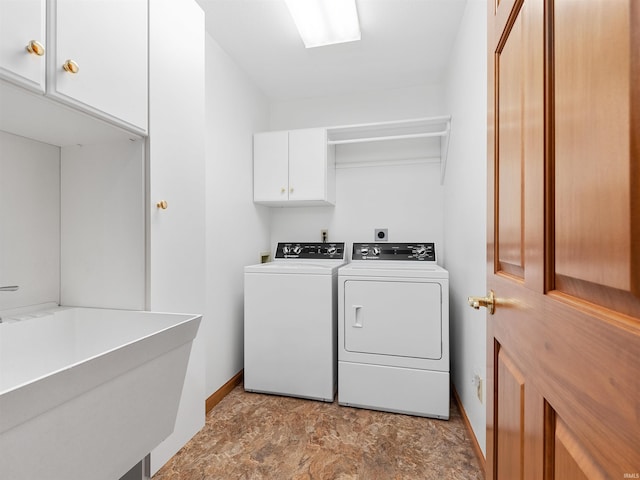 laundry room with baseboards, cabinet space, a sink, stone finish floor, and washer and clothes dryer