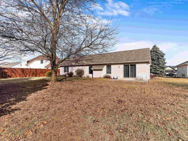 rear view of house with a yard and fence