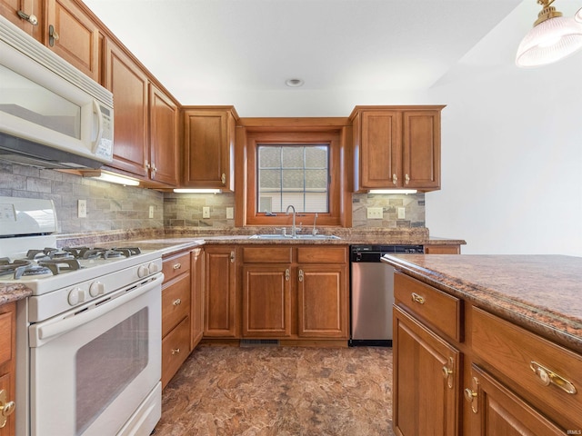 kitchen with brown cabinetry, decorative backsplash, white appliances, and a sink