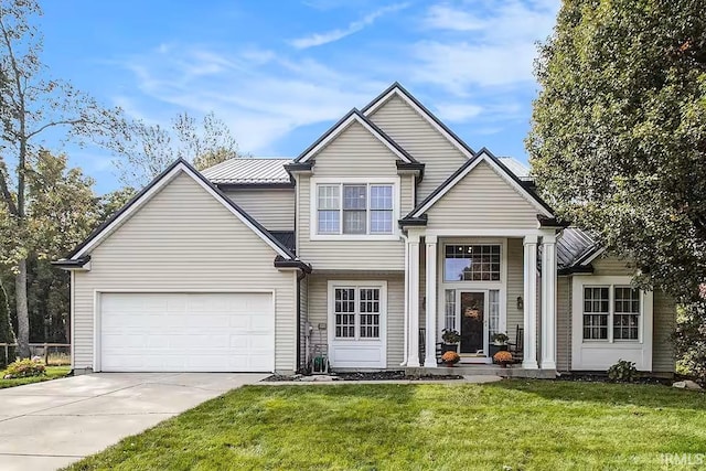 traditional home featuring a front yard, concrete driveway, an attached garage, and metal roof