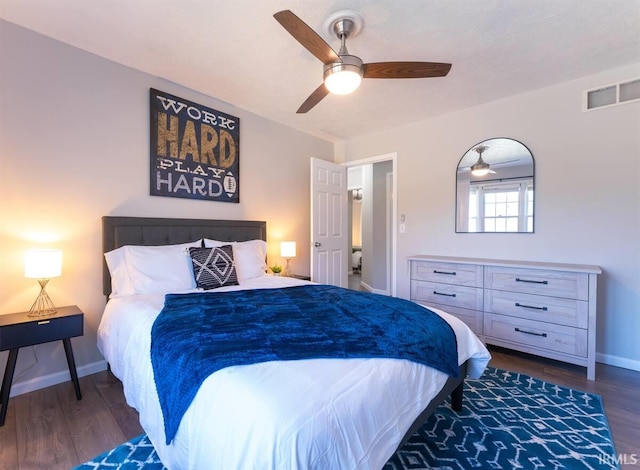 bedroom featuring dark wood-style floors, visible vents, a ceiling fan, and baseboards