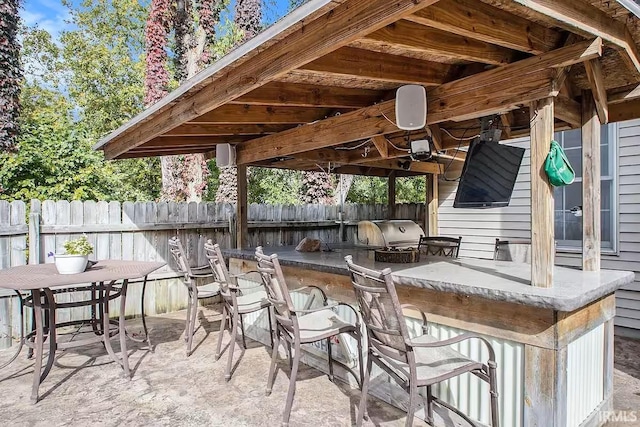 view of patio / terrace featuring exterior kitchen, a grill, fence, and outdoor dry bar