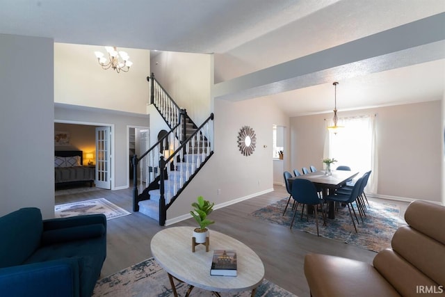 living area featuring high vaulted ceiling, wood finished floors, stairway, an inviting chandelier, and baseboards