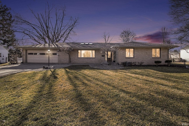 ranch-style home featuring brick siding, a lawn, an attached garage, and concrete driveway