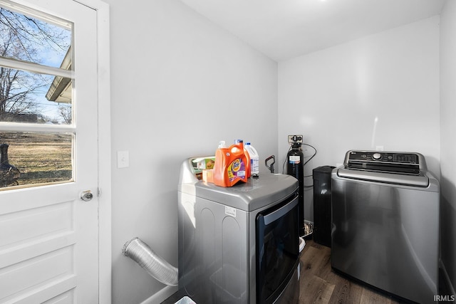 clothes washing area featuring separate washer and dryer, dark wood finished floors, and laundry area