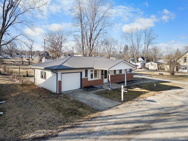 view of front of house featuring covered porch, concrete driveway, an attached garage, metal roof, and brick siding