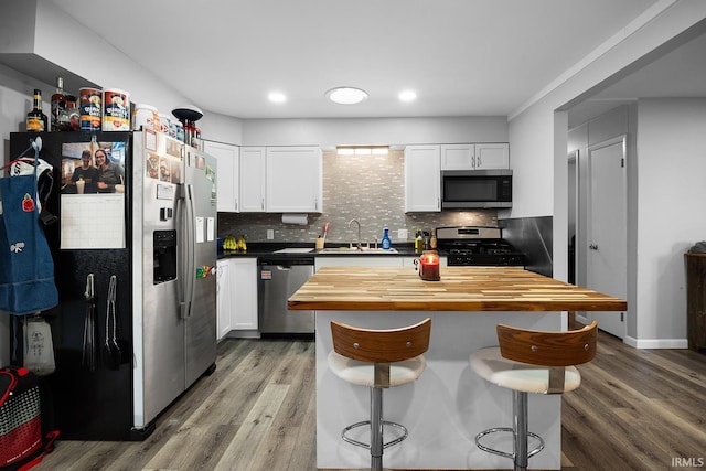 kitchen featuring a breakfast bar, light wood-style flooring, a sink, stainless steel appliances, and white cabinetry