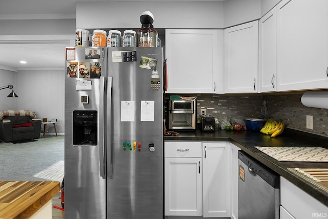 kitchen featuring dark countertops, decorative backsplash, appliances with stainless steel finishes, and white cabinetry