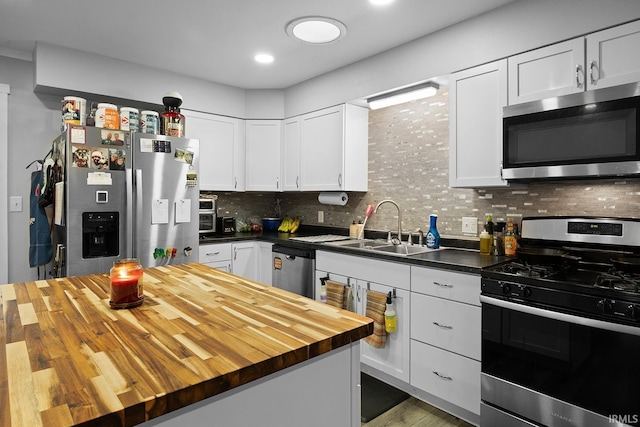 kitchen featuring a sink, wood counters, tasteful backsplash, stainless steel appliances, and white cabinets