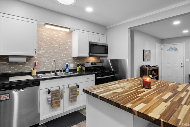 kitchen featuring wooden counters, a sink, decorative backsplash, appliances with stainless steel finishes, and white cabinetry