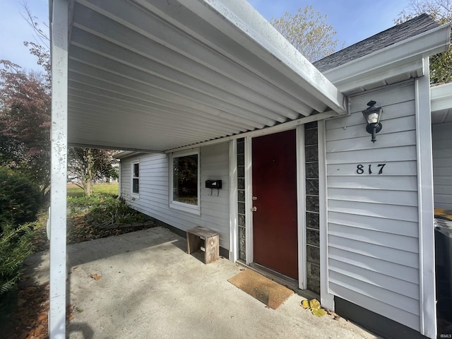 view of exterior entry featuring roof with shingles