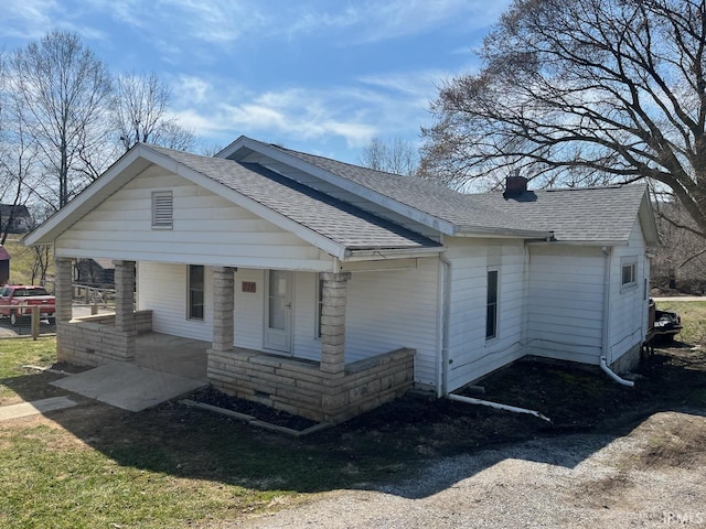 view of front of house with covered porch, a chimney, and roof with shingles