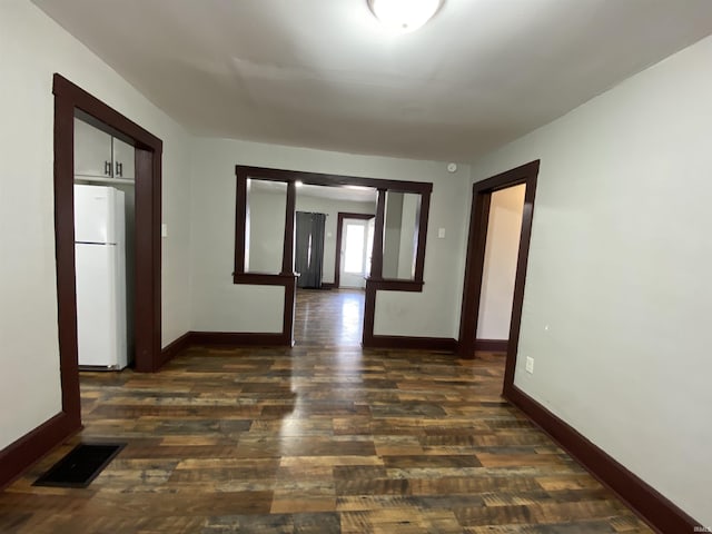 hallway with visible vents, dark wood-type flooring, and baseboards