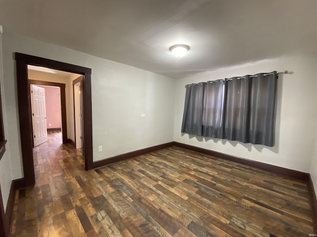 spare room featuring baseboards and dark wood finished floors