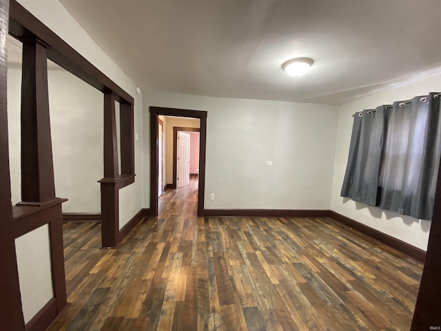 spare room with dark wood finished floors and baseboards