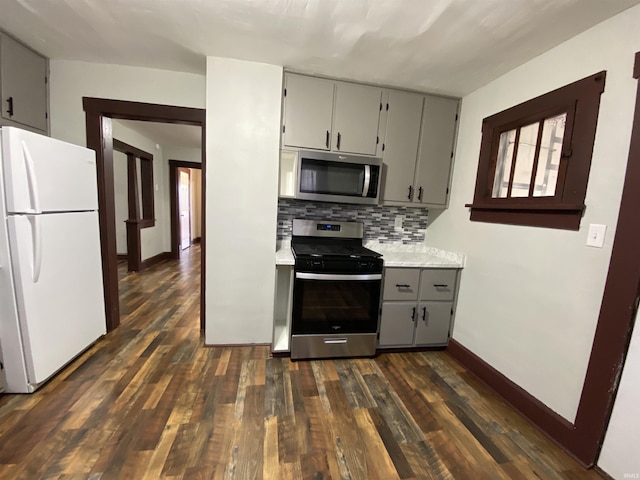 kitchen featuring tasteful backsplash, dark wood-type flooring, light countertops, gray cabinets, and stainless steel appliances