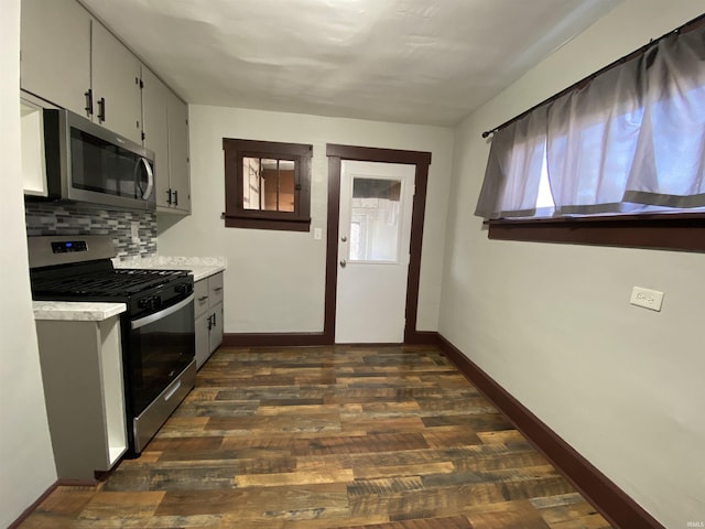 kitchen with dark wood finished floors, backsplash, stainless steel appliances, light countertops, and a wealth of natural light