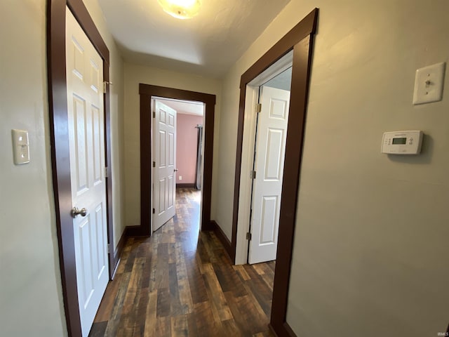 hall featuring baseboards and dark wood-style flooring