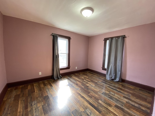 unfurnished room with baseboards and dark wood-style floors