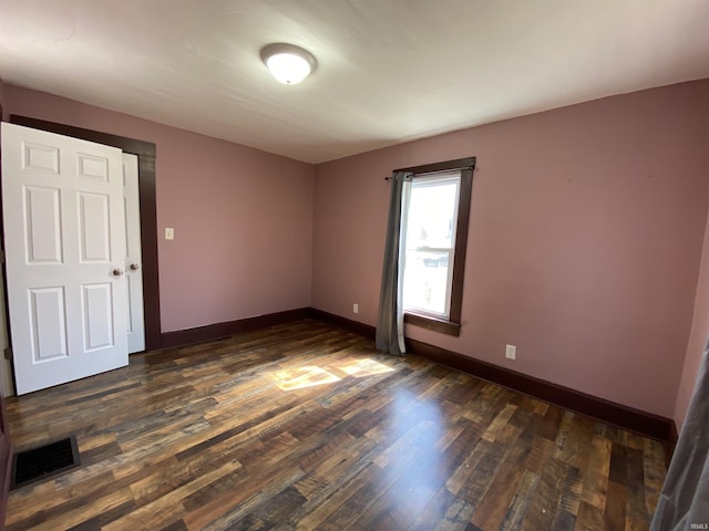 spare room with visible vents, baseboards, and dark wood-style flooring