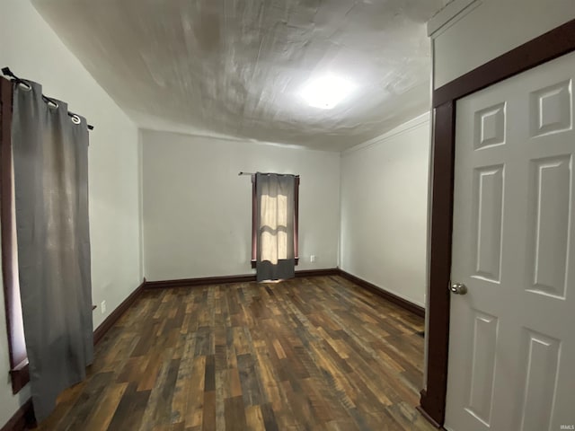 empty room featuring dark wood-type flooring and baseboards