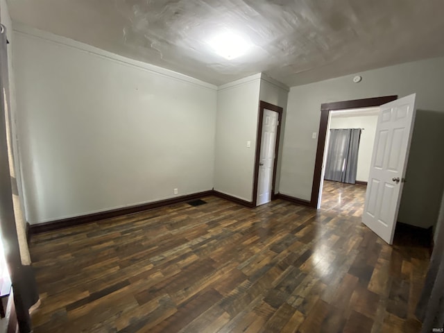 spare room featuring baseboards and dark wood finished floors